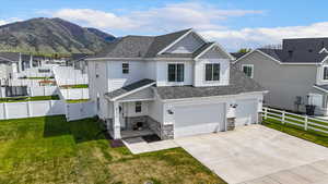 View of front of property with concrete driveway, fence, stone siding, and a front lawn