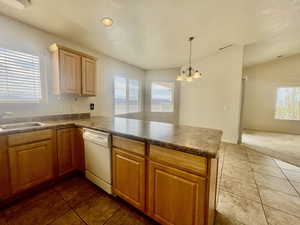 Kitchen featuring a peninsula, tile patterned floors, a chandelier, a sink, and dishwasher
