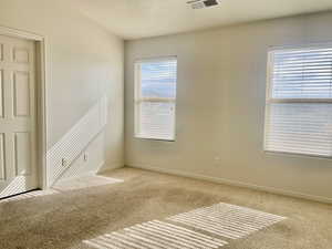 Spare room featuring carpet floors, baseboards, and visible vents