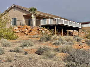 Rear view of property featuring stucco siding and a wooden deck