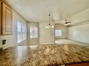 Interior space with lofted ceiling, carpet, and ceiling fan with notable chandelier