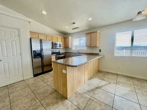 Kitchen featuring visible vents, a peninsula, light brown cabinets, dark countertops, and appliances with stainless steel finishes