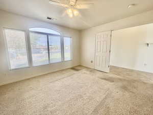 Carpeted spare room featuring visible vents, a ceiling fan, and baseboards
