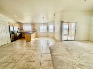 Kitchen with light tile patterned floors, baseboards, open floor plan, light brown cabinets, and stainless steel appliances