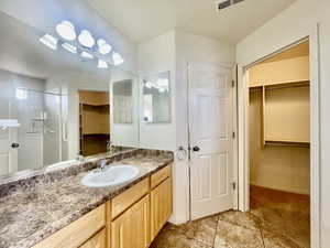 Bathroom featuring a walk in closet, a shower with shower door, tile patterned flooring, vanity, and visible vents