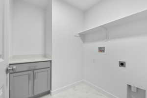 Washroom with marble finish floor, baseboards, cabinet space, washer hookup, and hookup for an electric dryer