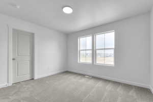 Carpeted spare room with baseboards, a textured ceiling, and visible vents
