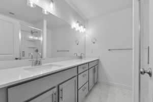 Full bathroom featuring a sink, a stall shower, double vanity, and marble finish floor