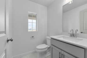 Half bath featuring toilet, baseboards, marble finish floor, and vanity