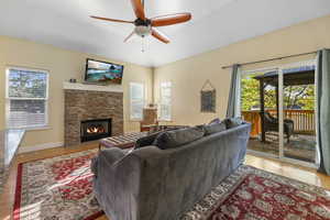Living room featuring visible vents, wood finished floors, a fireplace, baseboards, and ceiling fan