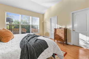 Bedroom featuring baseboards, vaulted ceiling, and light wood-type flooring