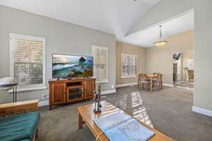 Carpeted living room with baseboards, vaulted ceiling, and arched walkways