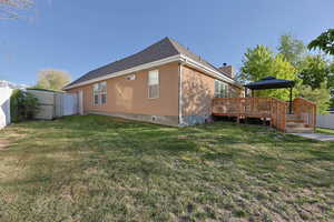 View of home's exterior with fence, a gazebo, a deck, a chimney, and a yard