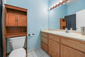 Full bath featuring tile patterned flooring, vanity, toilet, baseboards, and a shower with shower curtain