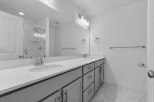 Bathroom featuring double vanity, a sink, marble finish floor, and a shower with shower door