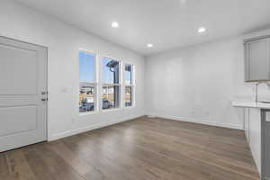 Unfurnished dining area featuring a sink, baseboards, recessed lighting, and wood finished floors