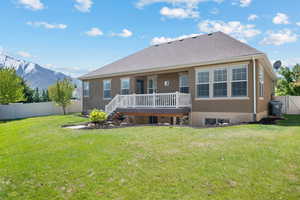 Rear view of property featuring stucco siding, a fenced backyard, a deck with mountain view, and a yard