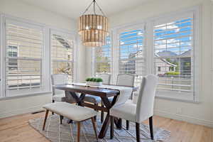 Dining space featuring baseboards, wood finished floors, visible vents, and an inviting chandelier