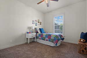 Carpeted bedroom featuring baseboards and ceiling fan