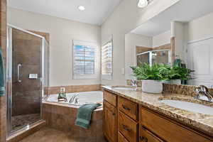 Bathroom featuring double vanity, a sink, a garden tub, and a stall shower