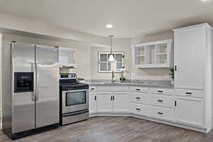 Kitchen featuring a sink, open shelves, stainless steel appliances, and white cabinetry