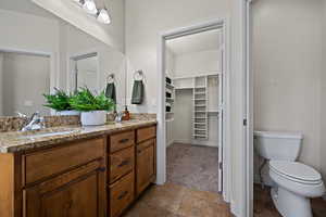 Full bath featuring double vanity, toilet, a walk in closet, and a sink
