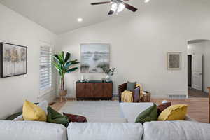 Living area featuring ceiling fan, arched walkways, baseboards, lofted ceiling, and recessed lighting