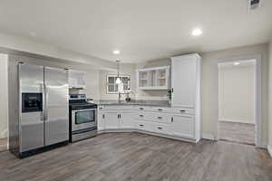 Kitchen with a sink, dark wood finished floors, stainless steel appliances, white cabinetry, and visible vents