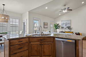Kitchen featuring stainless steel dishwasher, open floor plan, plenty of natural light, a sink, and light wood finished floors