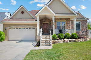 View of front of house featuring an attached garage, stucco siding, driveway, and stone siding