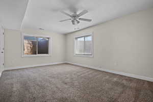 Spare room featuring baseboards, carpet flooring, a ceiling fan, and visible vents