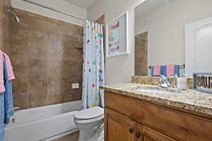 Bathroom with toilet, tile patterned floors, shower / tub combo with curtain, and vanity