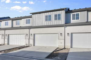 View of property with board and batten siding, driveway, and a garage