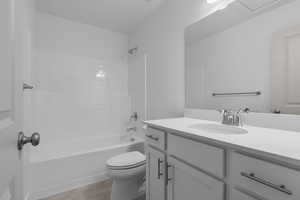 Bathroom featuring vanity, bathtub / shower combination, toilet, and wood finished floors