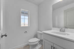 Half bath with vanity, baseboards, and toilet