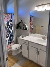 Full bath with toilet, curtained shower, and vanity
