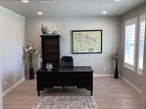 Office featuring light wood-style floors, baseboards, recessed lighting, and a textured ceiling