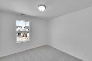 Empty room featuring visible vents, a textured ceiling, baseboards, and light carpet