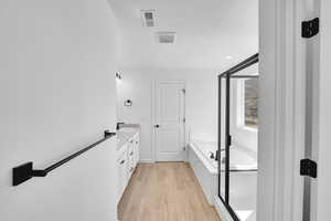 Full bath with a garden tub, visible vents, wood finished floors, vanity, and a shower with door