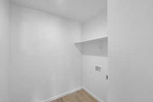 Laundry room with laundry area, washer hookup, light wood-style floors, baseboards, and electric dryer hookup