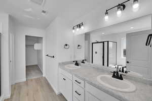 Bathroom featuring a sink, a stall shower, double vanity, and visible vents