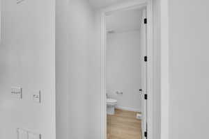 Bathroom with toilet, baseboards, visible vents, and wood finished floors