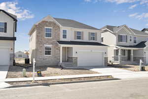 View of front of house with an attached garage, concrete driveway, and stone siding