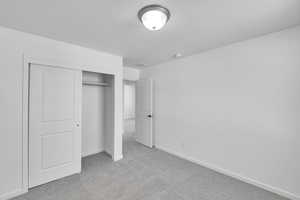 Unfurnished bedroom featuring carpet floors, baseboards, a closet, and a textured ceiling