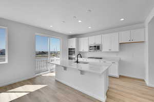 Kitchen featuring stainless steel appliances, baseboards, recessed lighting, and light wood finished floors