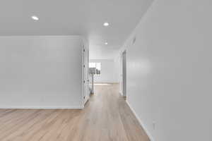 Hall featuring baseboards, light wood-type flooring, and recessed lighting