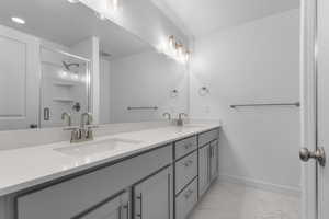 Full bathroom featuring double vanity, a sink, marble finish floor, and a stall shower