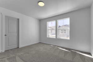 Empty room featuring carpet flooring, a textured ceiling, baseboards, and visible vents