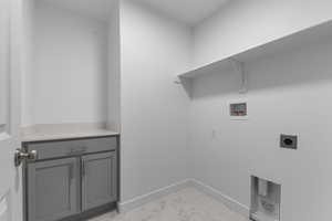 Laundry area featuring hookup for an electric dryer, cabinet space, baseboards, hookup for a washing machine, and marble finish floor