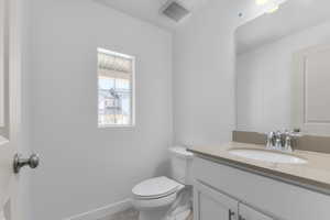 Half bath featuring toilet, visible vents, and vanity